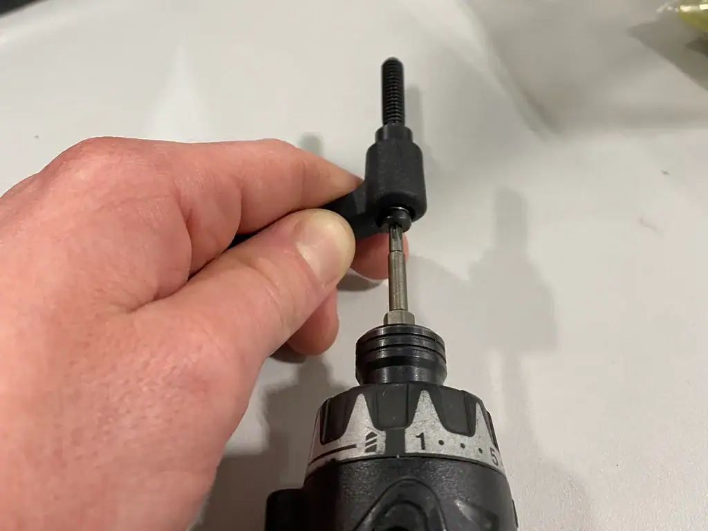 Hand holding a threaded handle subassembly while a power driver fastens it
