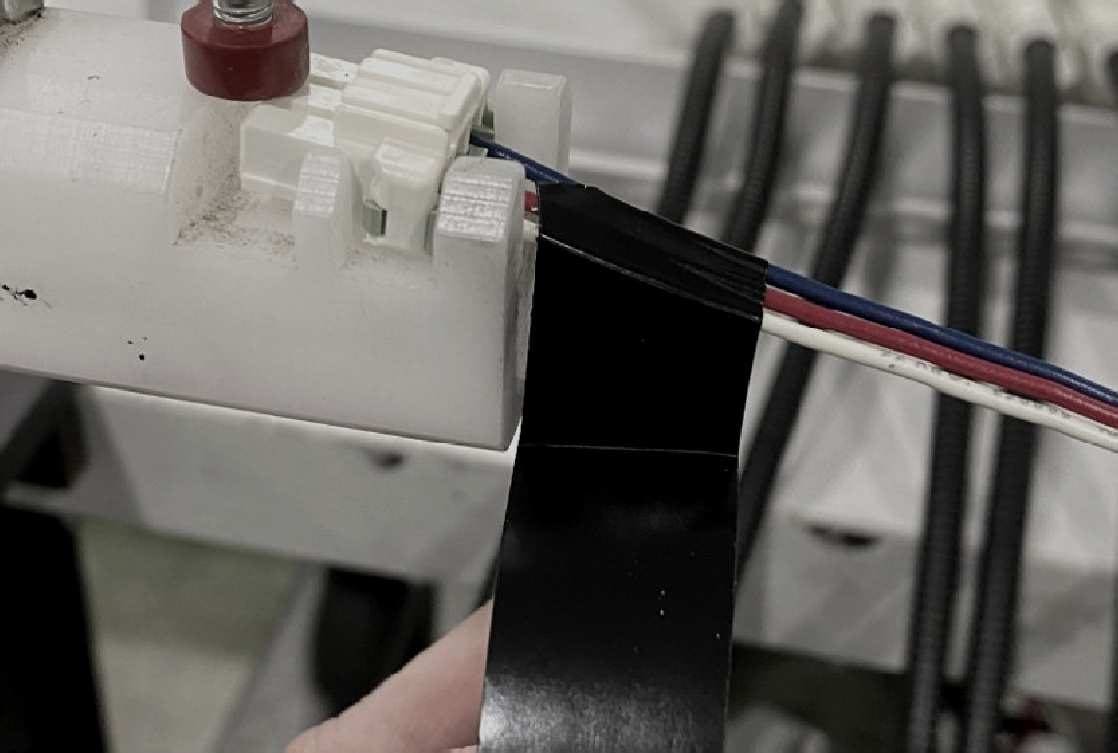 Black tape being applied to wire leads on a harness fixture