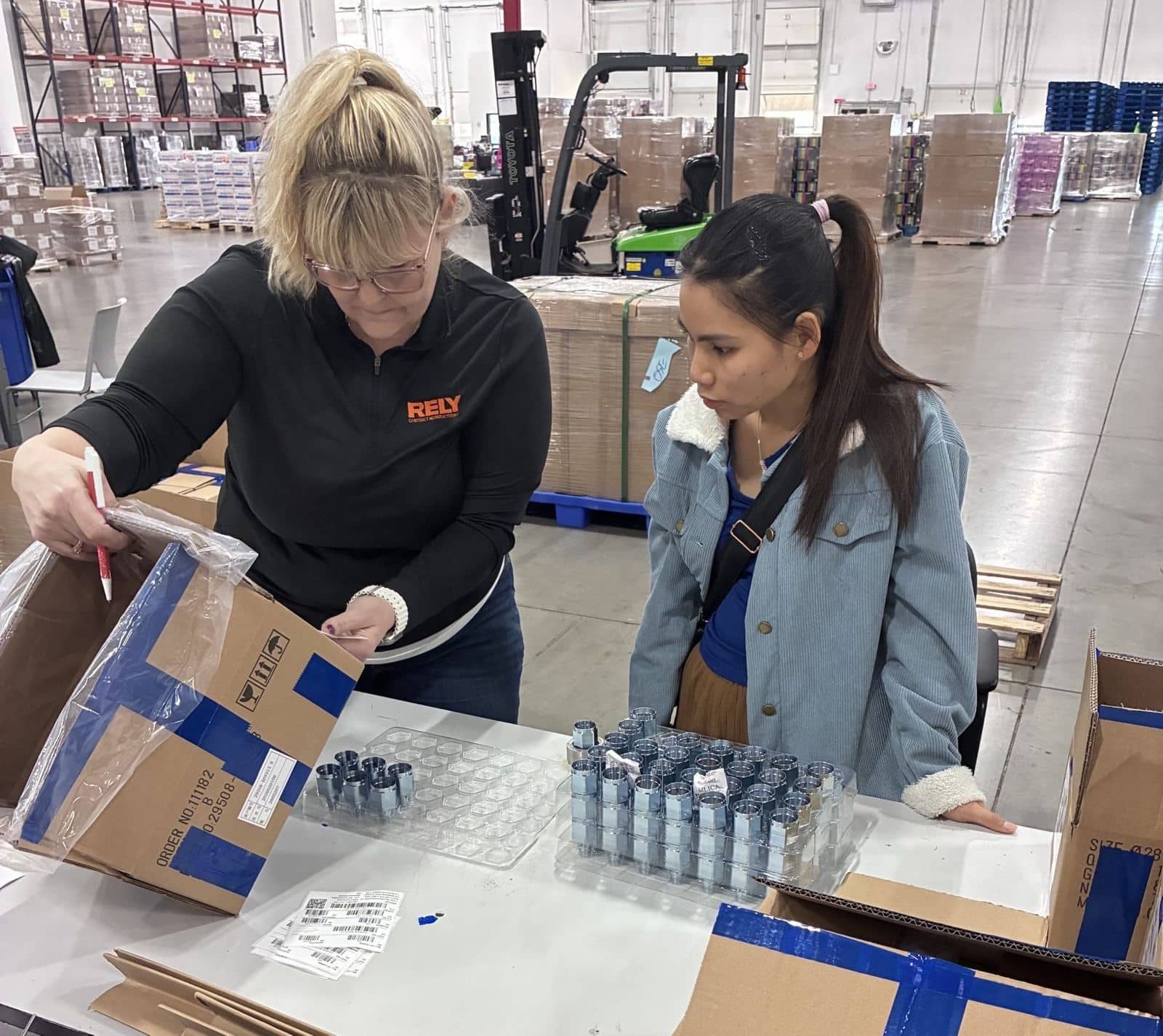 A RELY lead and an associate check bagged metal fittings against printed barcode labels before a repack