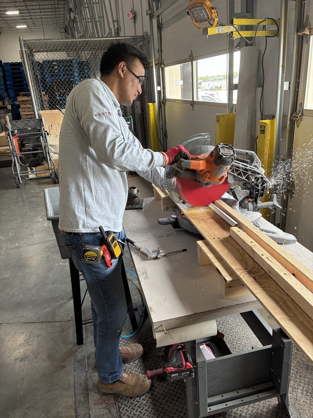 A RELY operator in safety glasses cutting PVC pipe to length at a saw station