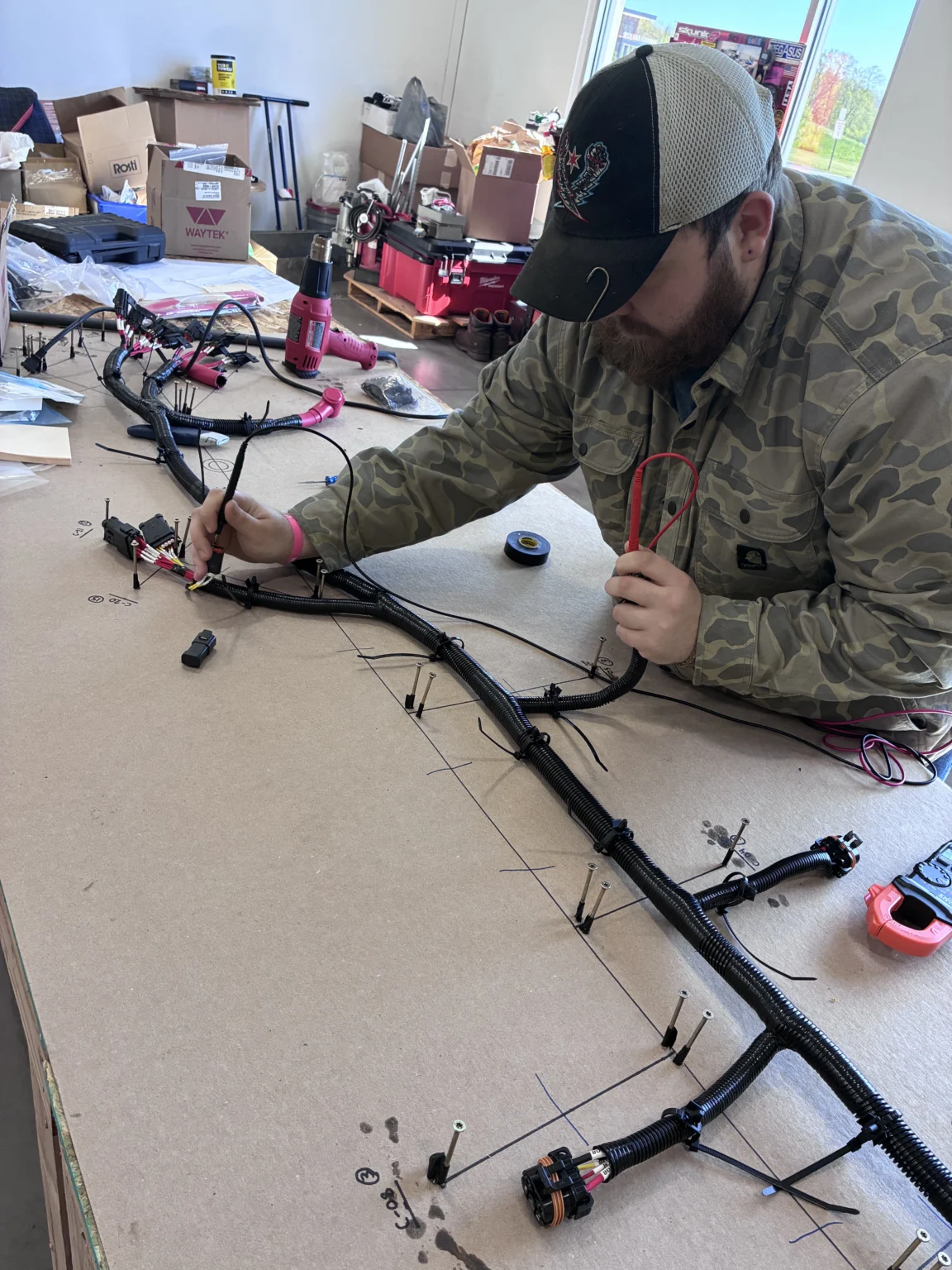 An operator routing a harness on a board before test