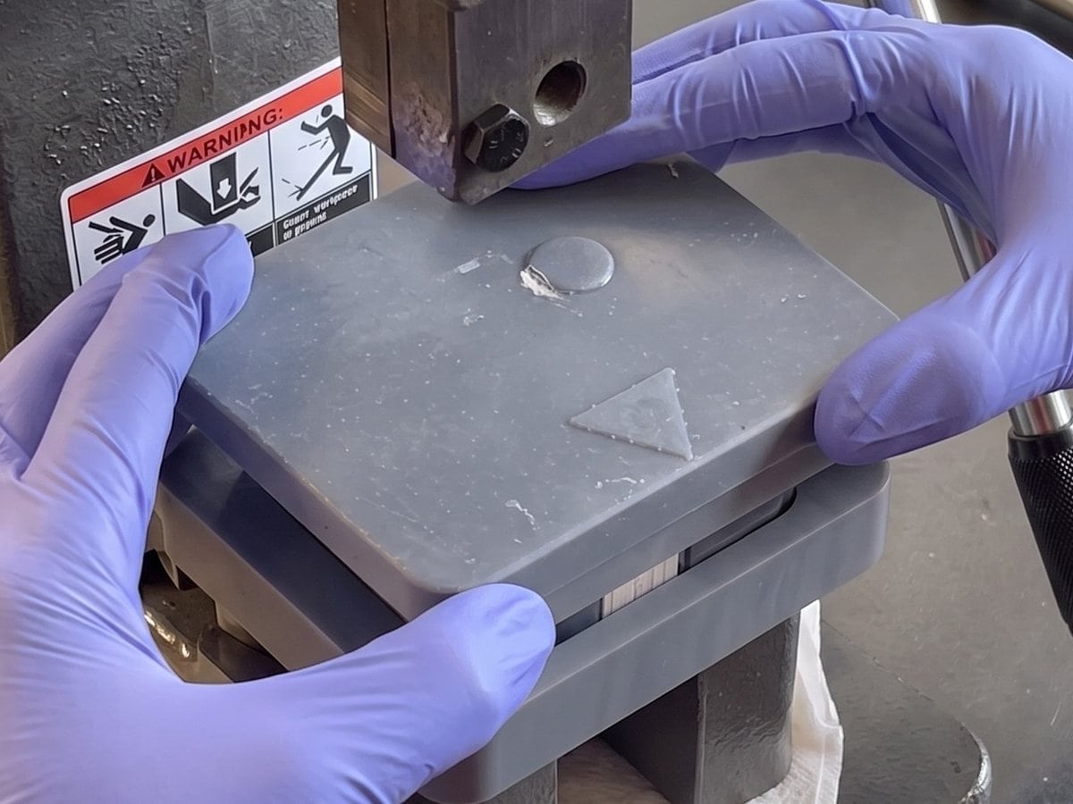 Operator seating a device cover plate with a hand press during the 2022 program